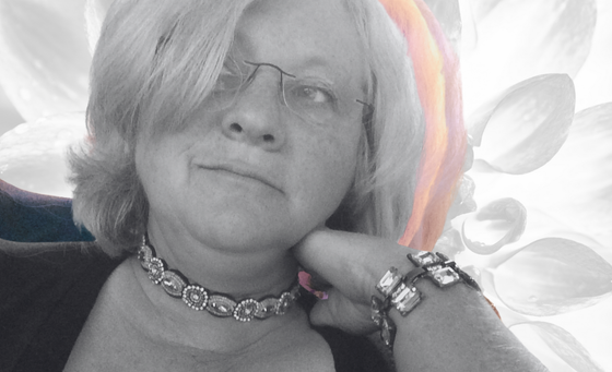 Mary Berry wearing glasses, necklace, and bracelet, hand on cheek, looking to the side with black and white background.