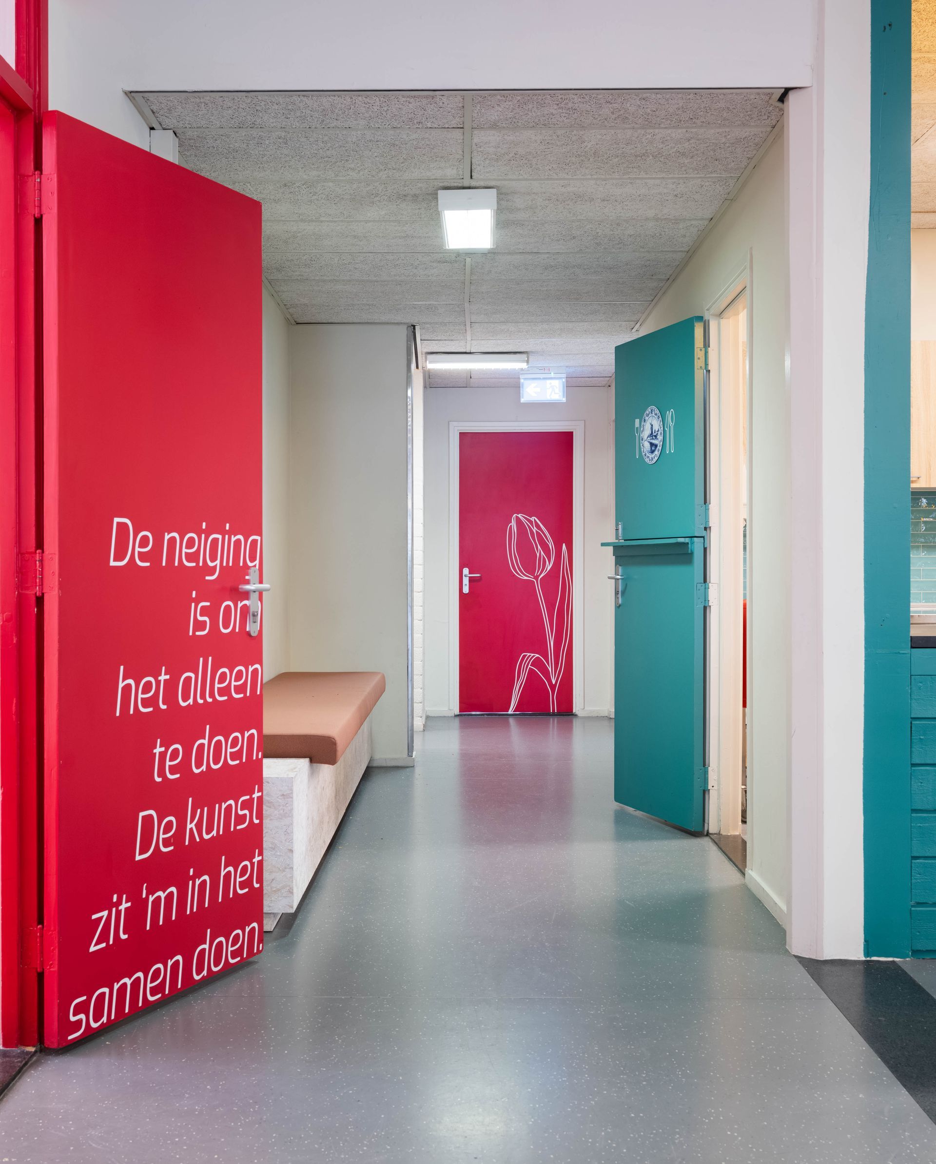 Gang met open deuren; één rode met tekst, één turquoise met een toiletsymbool en één rode met een eenvoudige tekening.