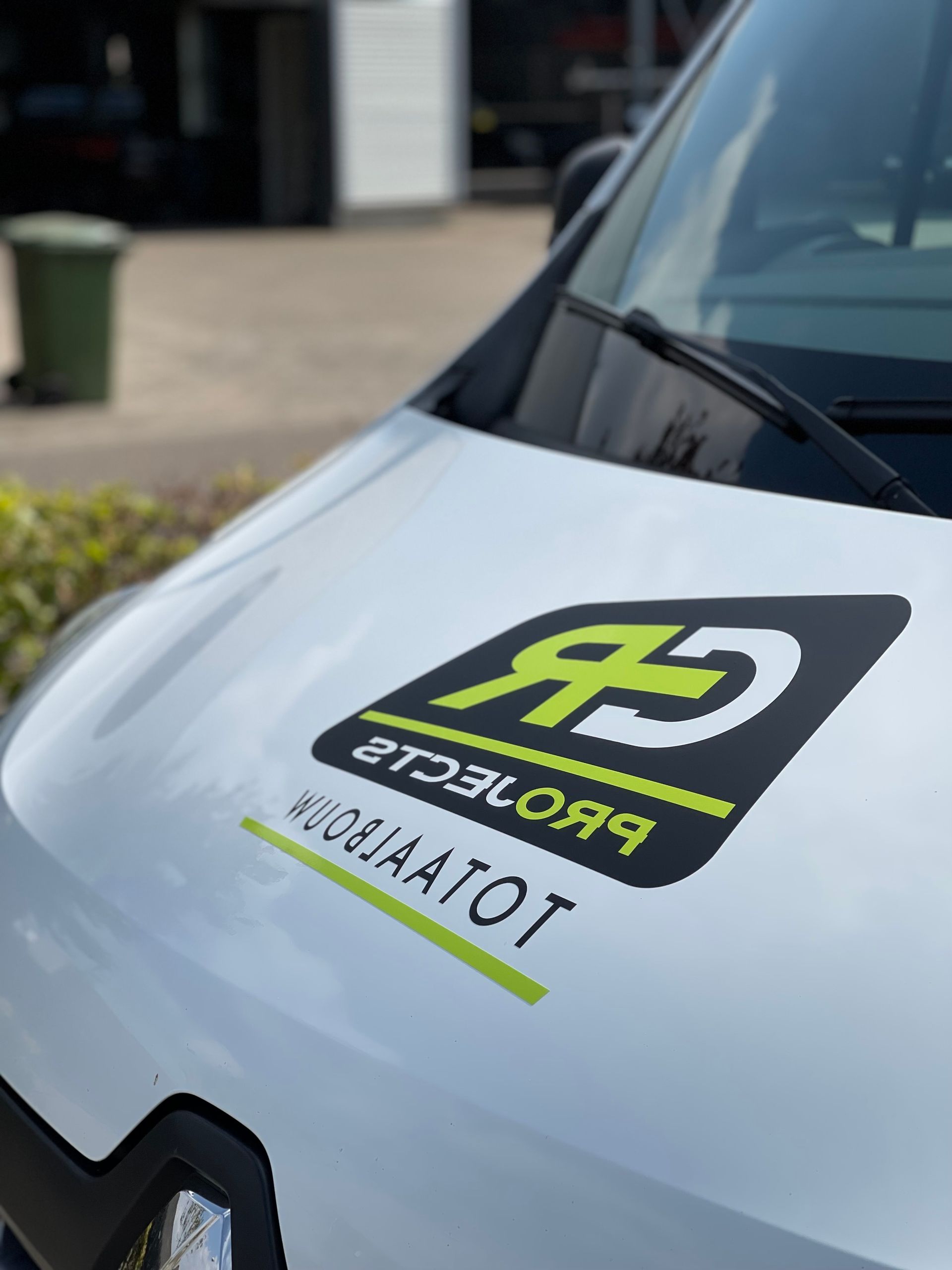 Een close-up van de motorkap van een witte bestelwagen met een logo erop