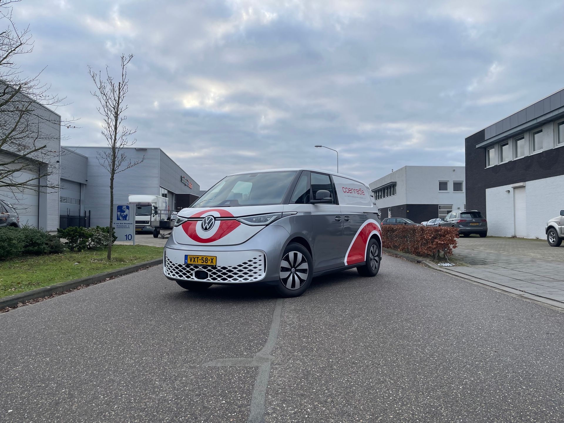 Een Volkswagenbusje rijdt door een straat naast een gebouw.