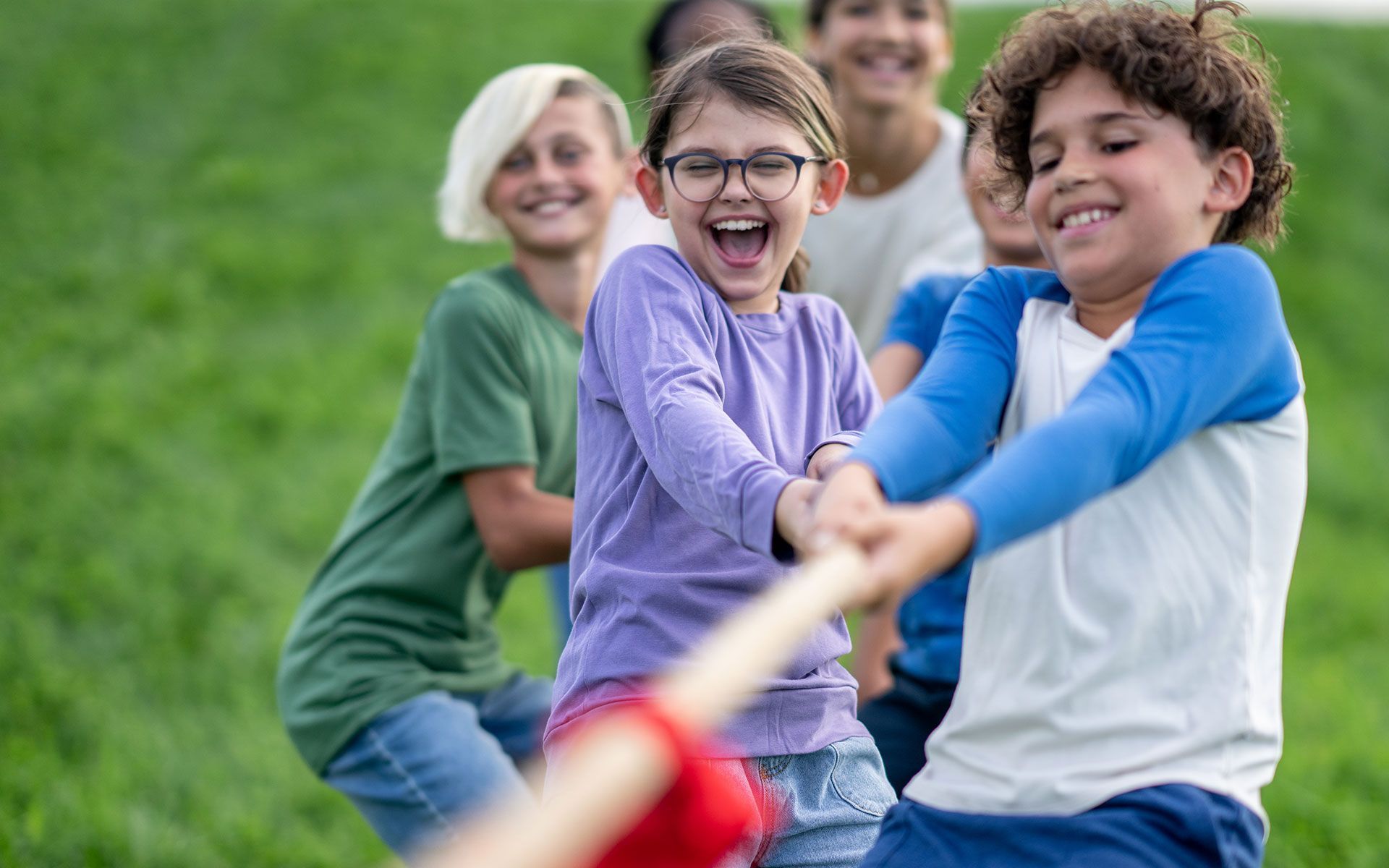 A small group of school aged children pull a rope.
