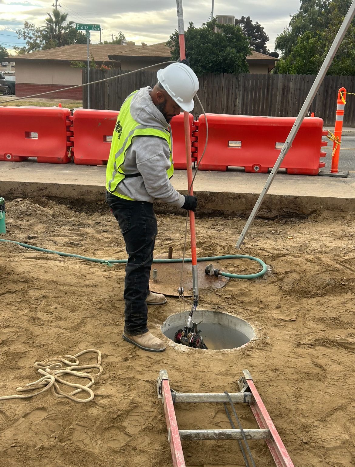 A man is standing on construction site dirt next to an open pipe, providing a pipeline video inspection.