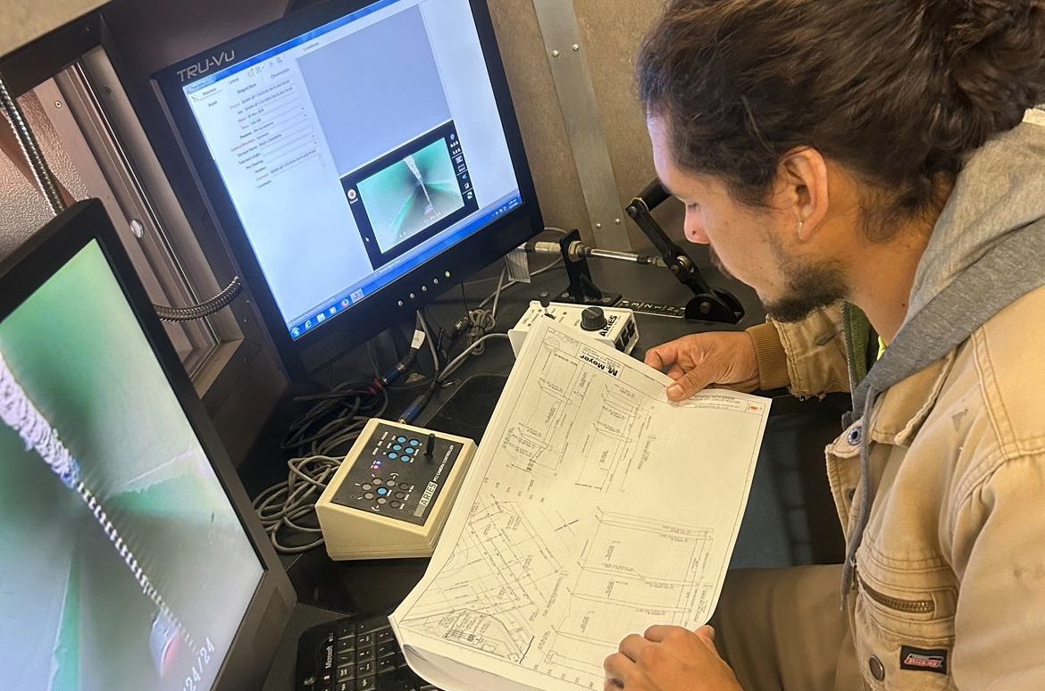 A man is sitting in front of a computer looking at a video inspection report.