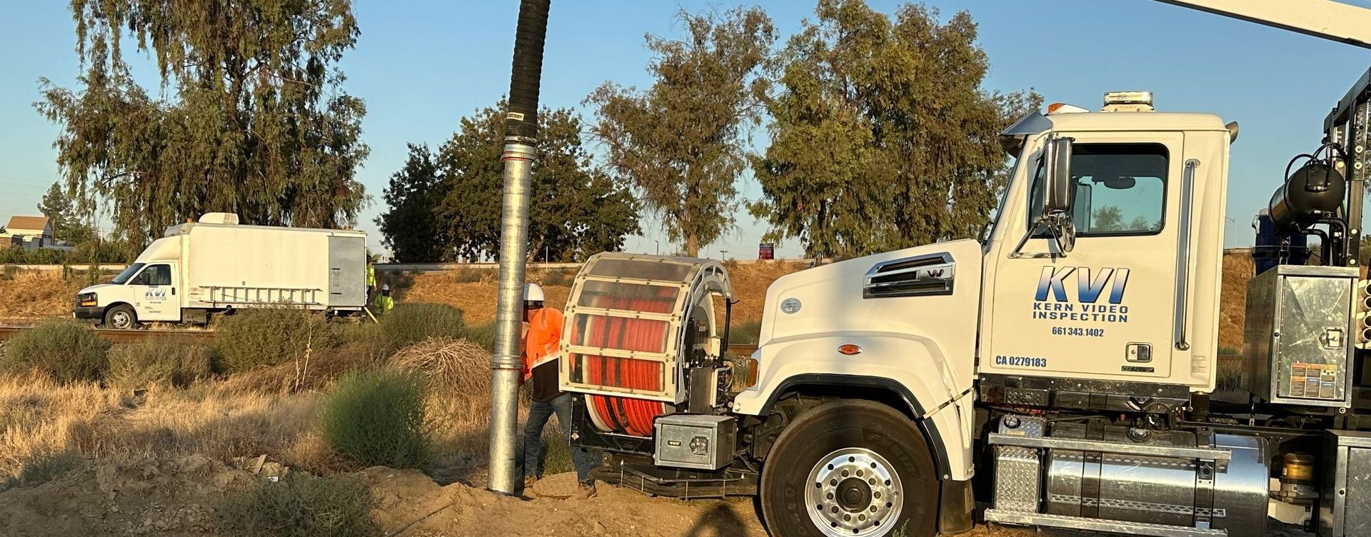 A white hydro vac truck is parked on in a field working on pipeline.