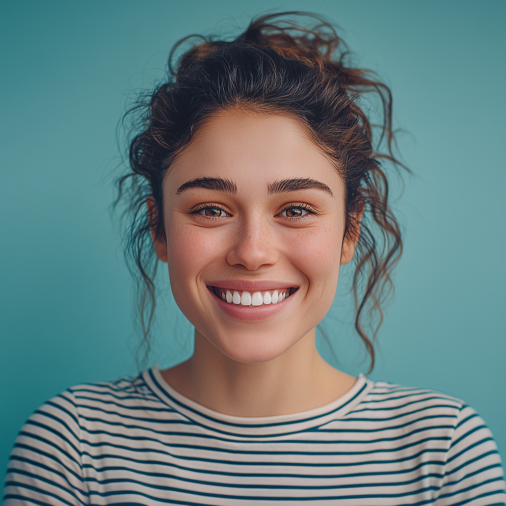Woman with brown hair in a bun, smiling widely, wearing a striped shirt, against a teal background.