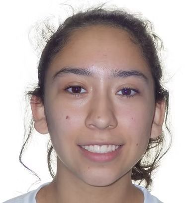 A person smiling, looking directly at the viewer, with light skin and dark hair.