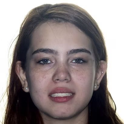 Woman with freckles smiles slightly, looking at the viewer; fair skin, brown hair, nose ring, two ear piercings.