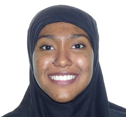 Person wearing a black head covering smiles at the camera, against a white background.