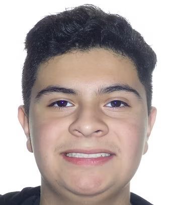Teenager smiles at the camera, dark hair and skin, against a white background.