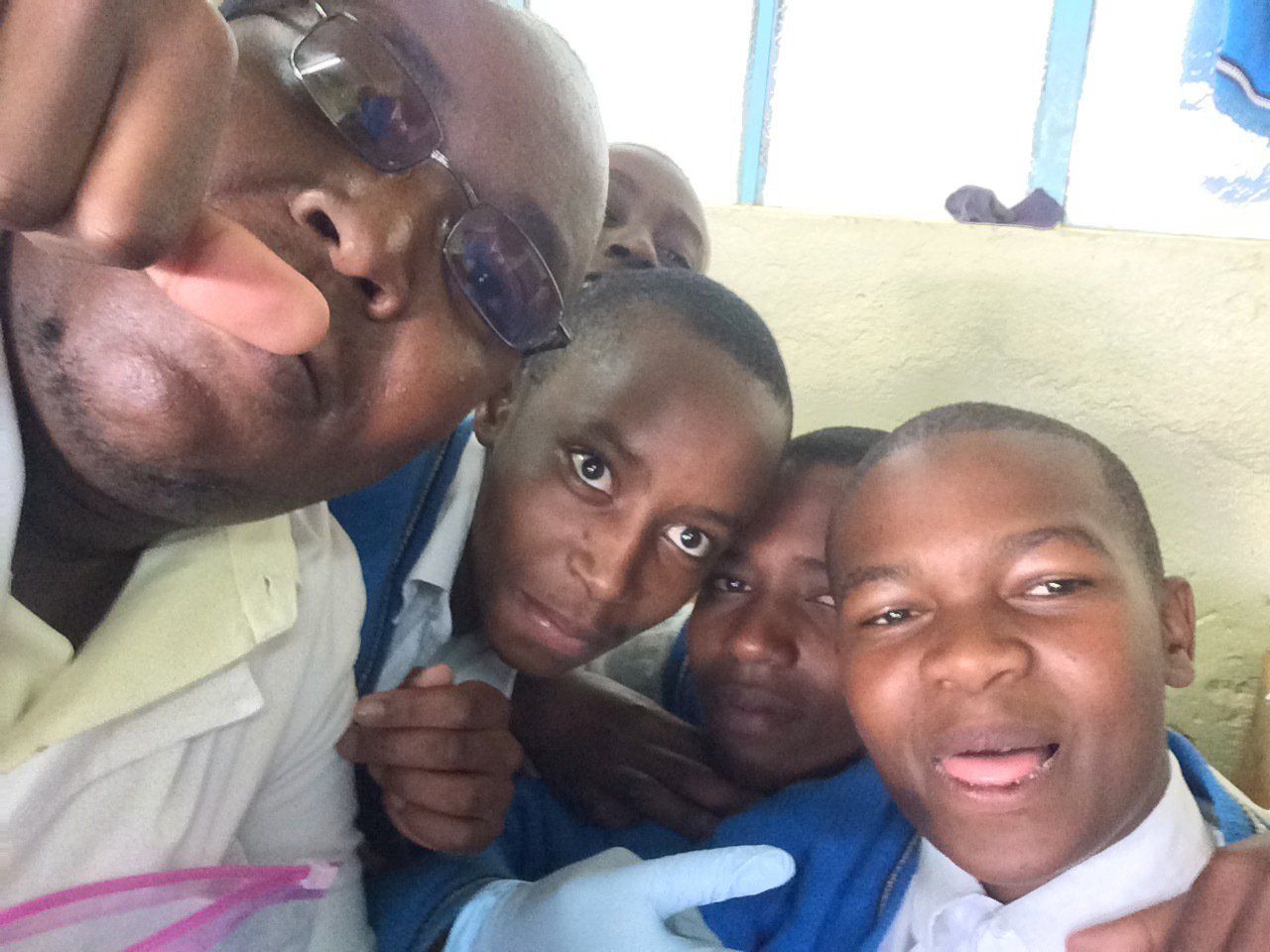 A group of young boys are posing for a picture with a man wearing sunglasses