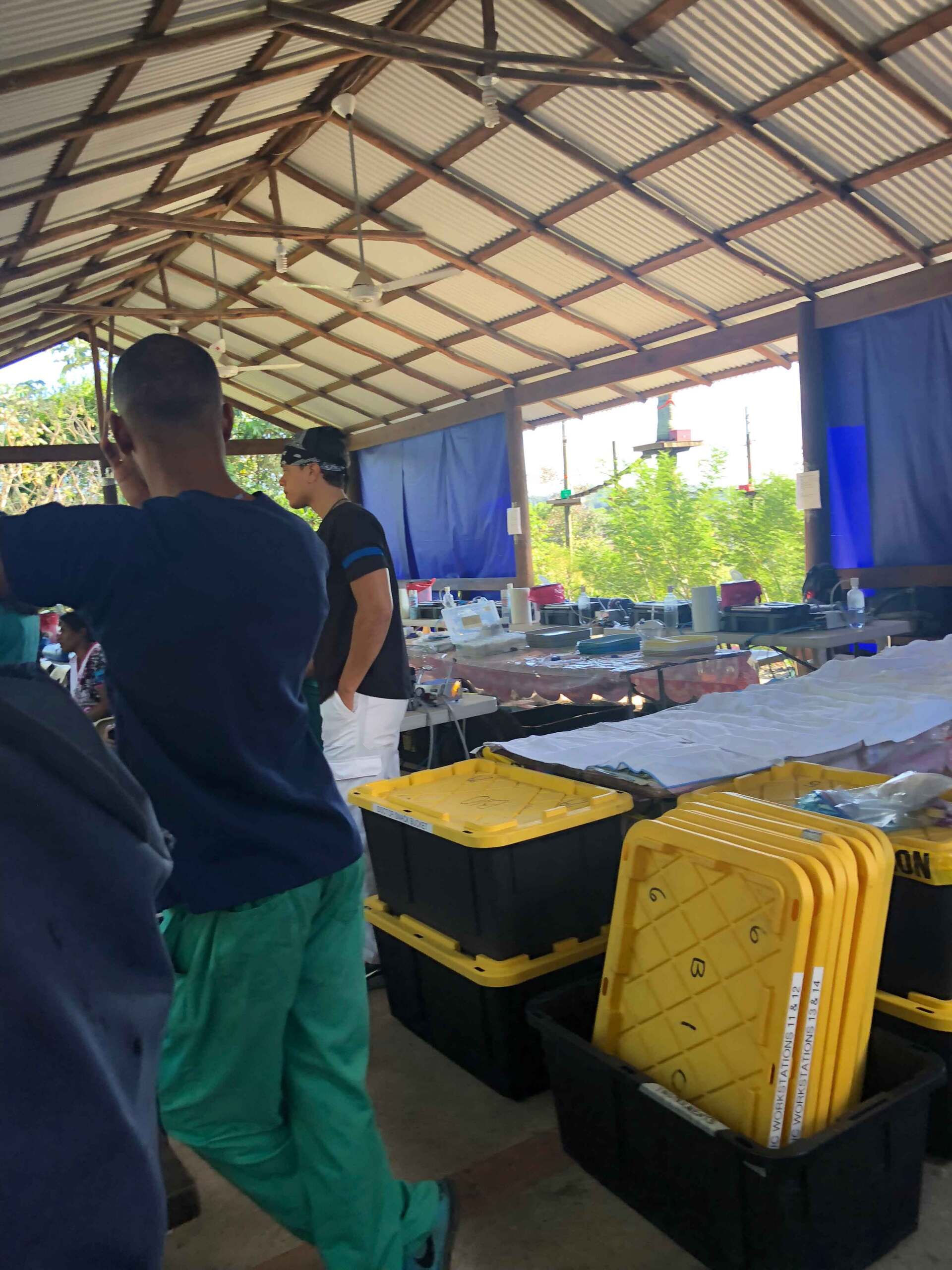 A man in green scrubs is standing in a room filled with yellow bins
