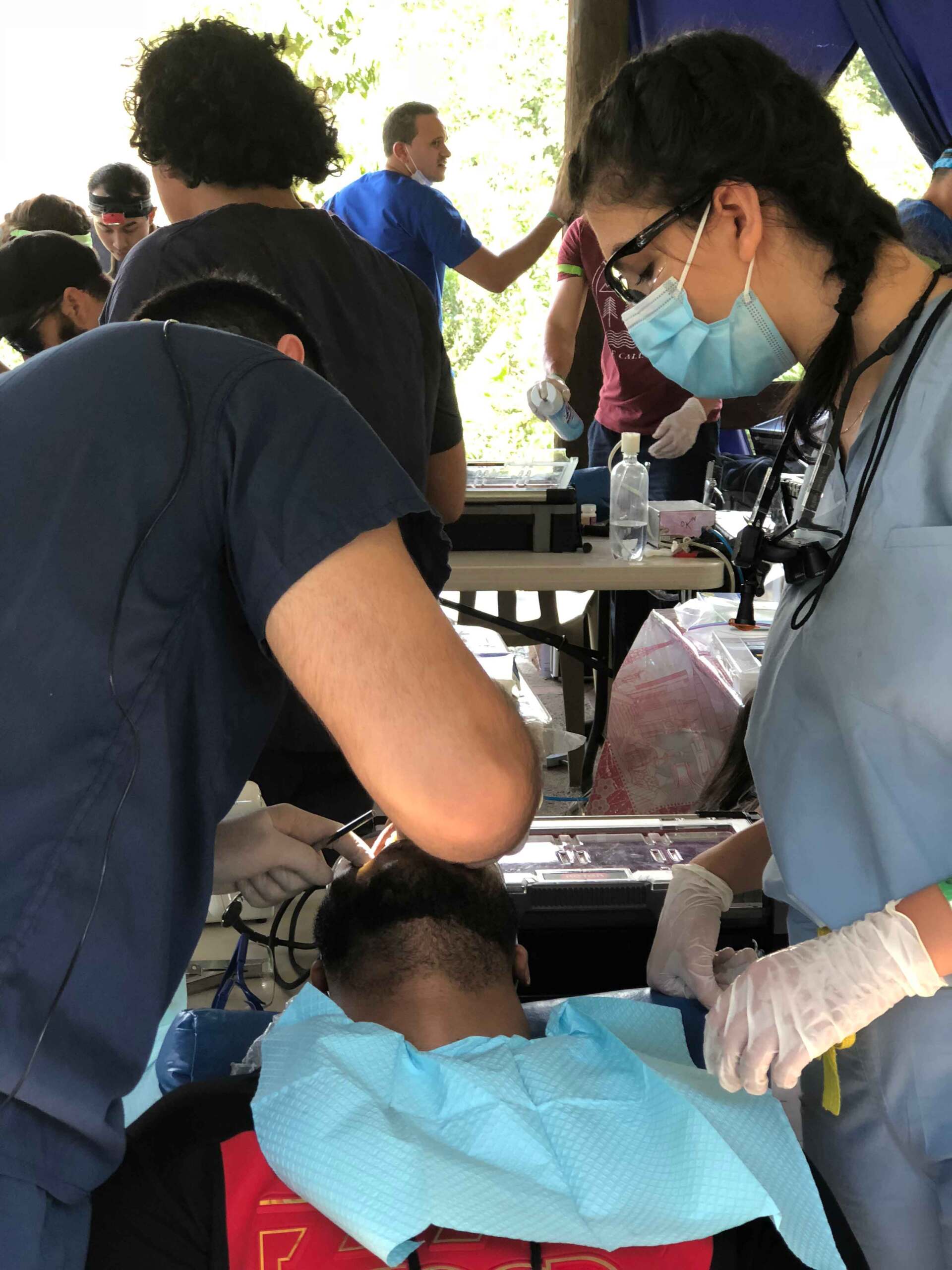 A woman wearing a mask is working on a child 's head