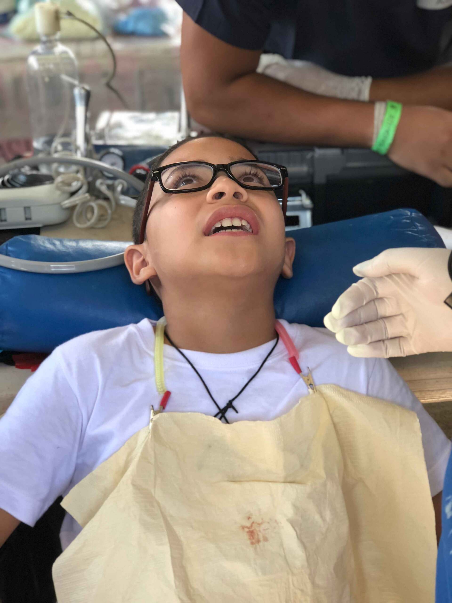 A young boy wearing glasses is laying in a dental chair