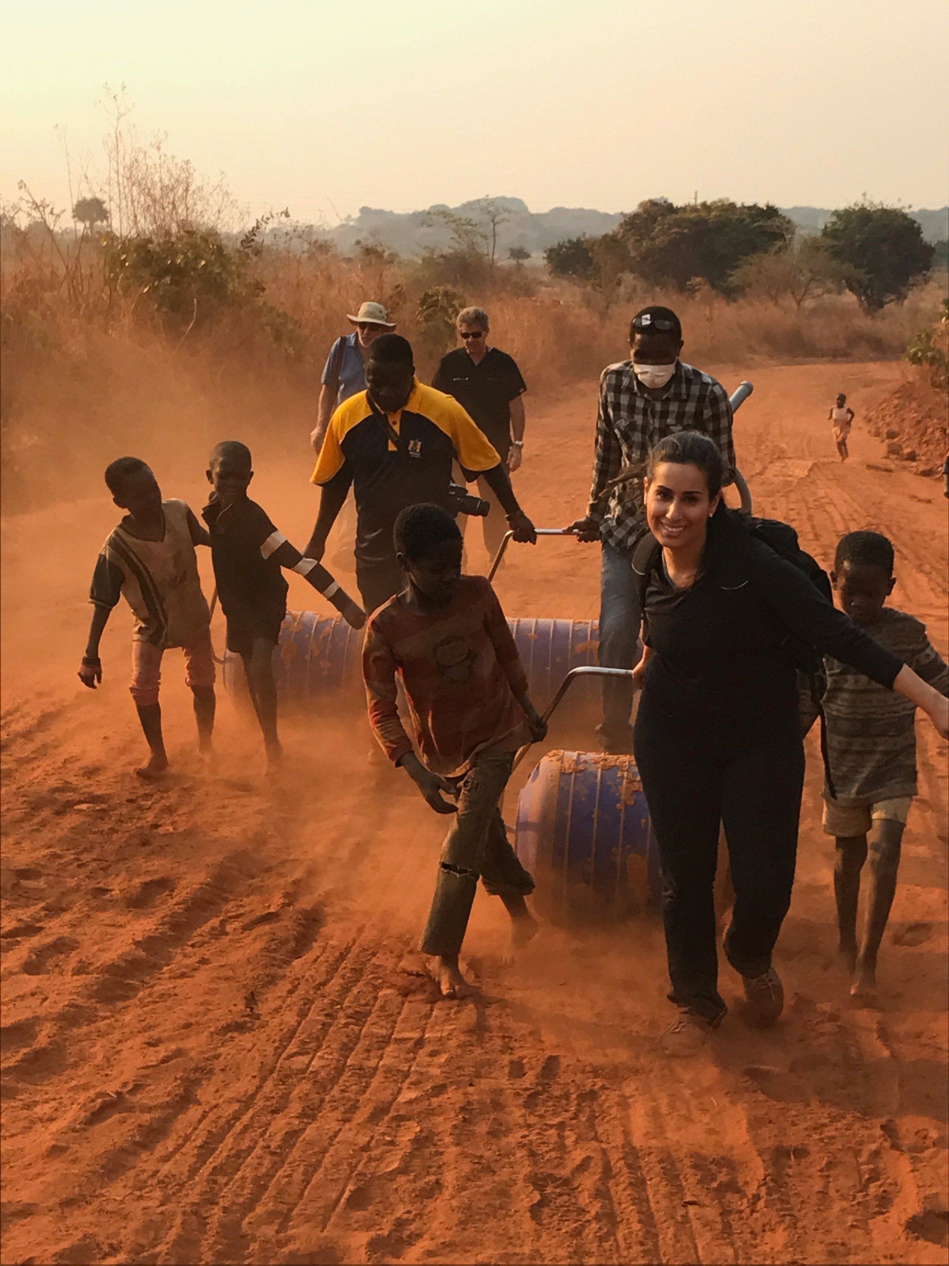 A group of people are walking down a dirt road
