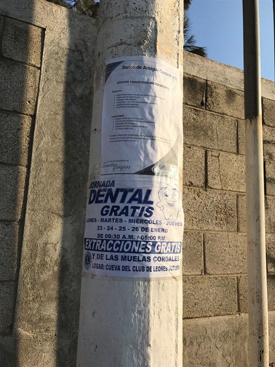 A sign on a pole that says dental gratis