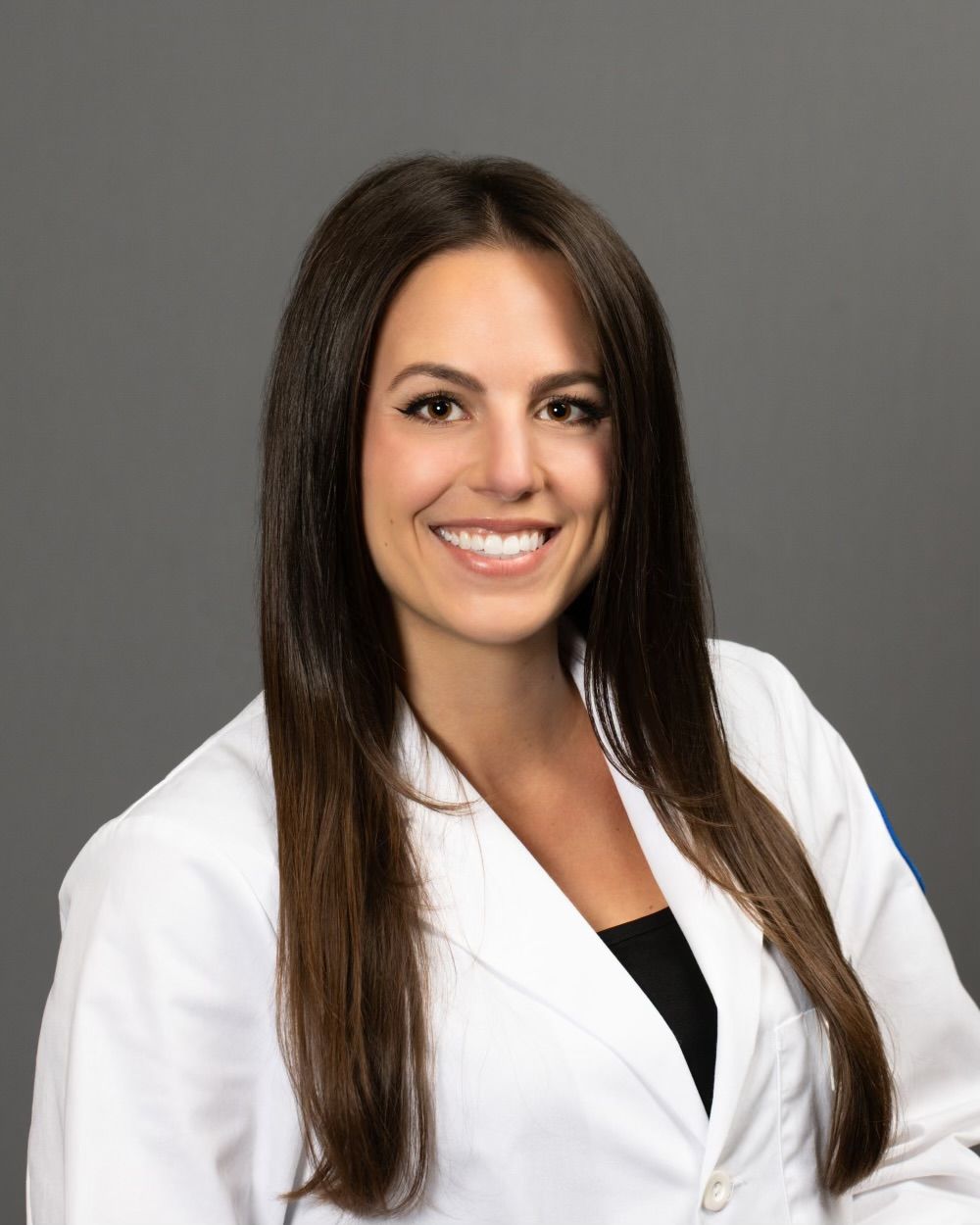 A woman in a white lab coat is smiling for the camera.