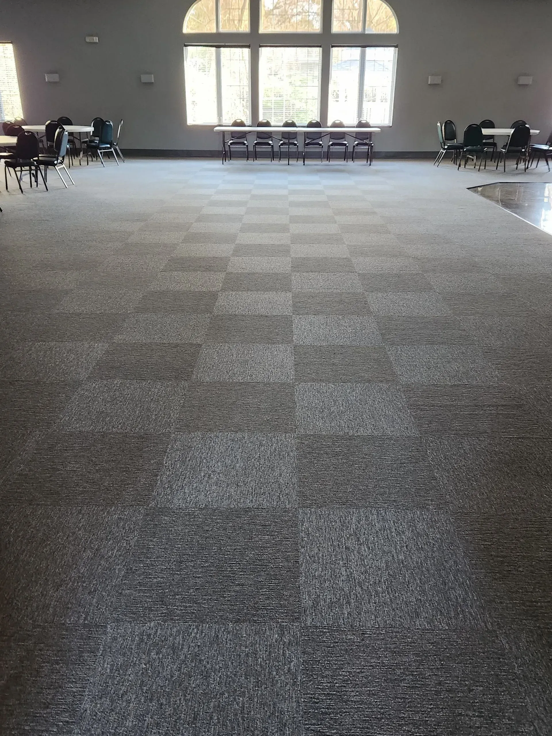 Large room with patterned carpet and tables set up near large windows.