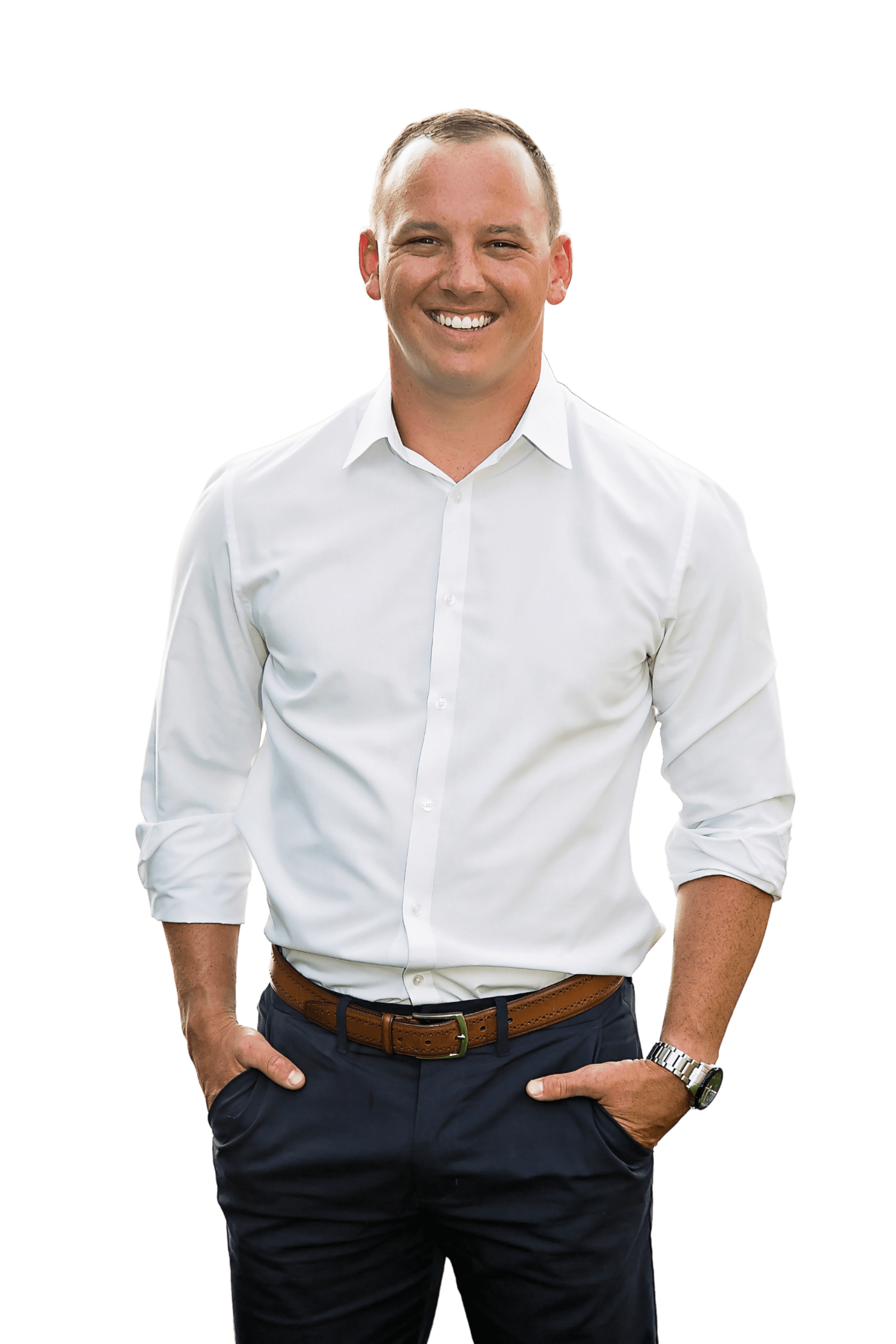 A man in a white shirt and blue pants is standing with his hands in his pockets.