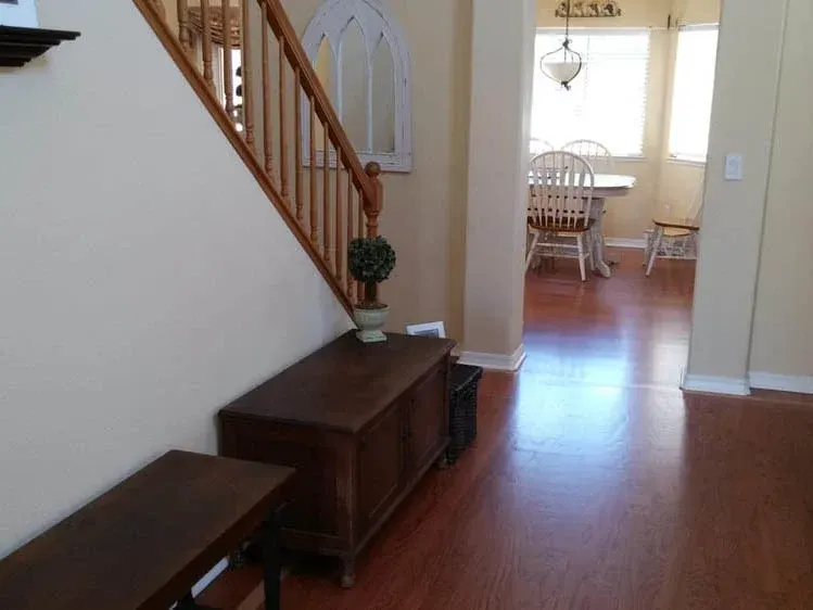 Wooden stairs and a dining area visible from an entry hall with a bench and storage chest.