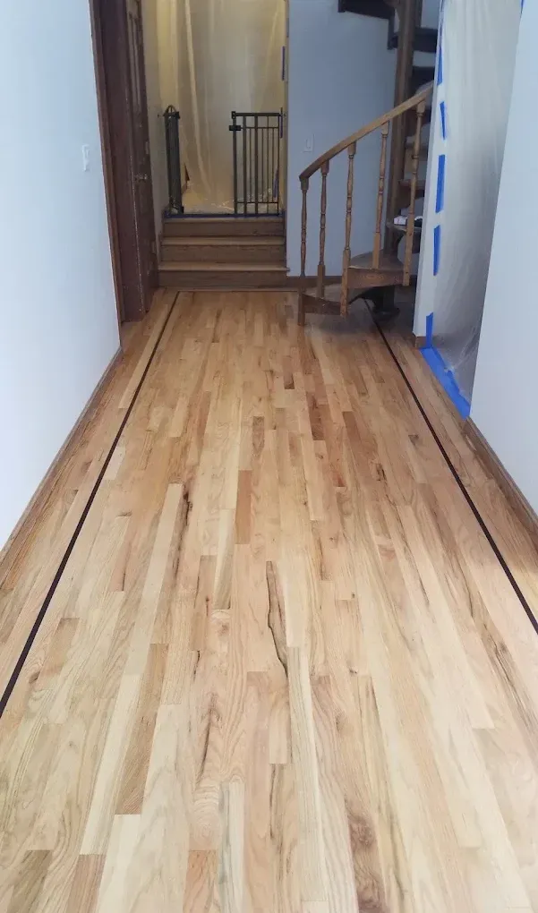 Hardwood hallway with dark border, leading to stairs. A spiral staircase is on the right.
