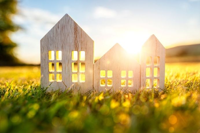 Three wooden houses are sitting on top of a lush green field.