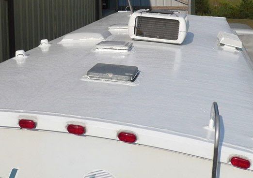 White RV roof with air conditioning unit, vents, and running lights.