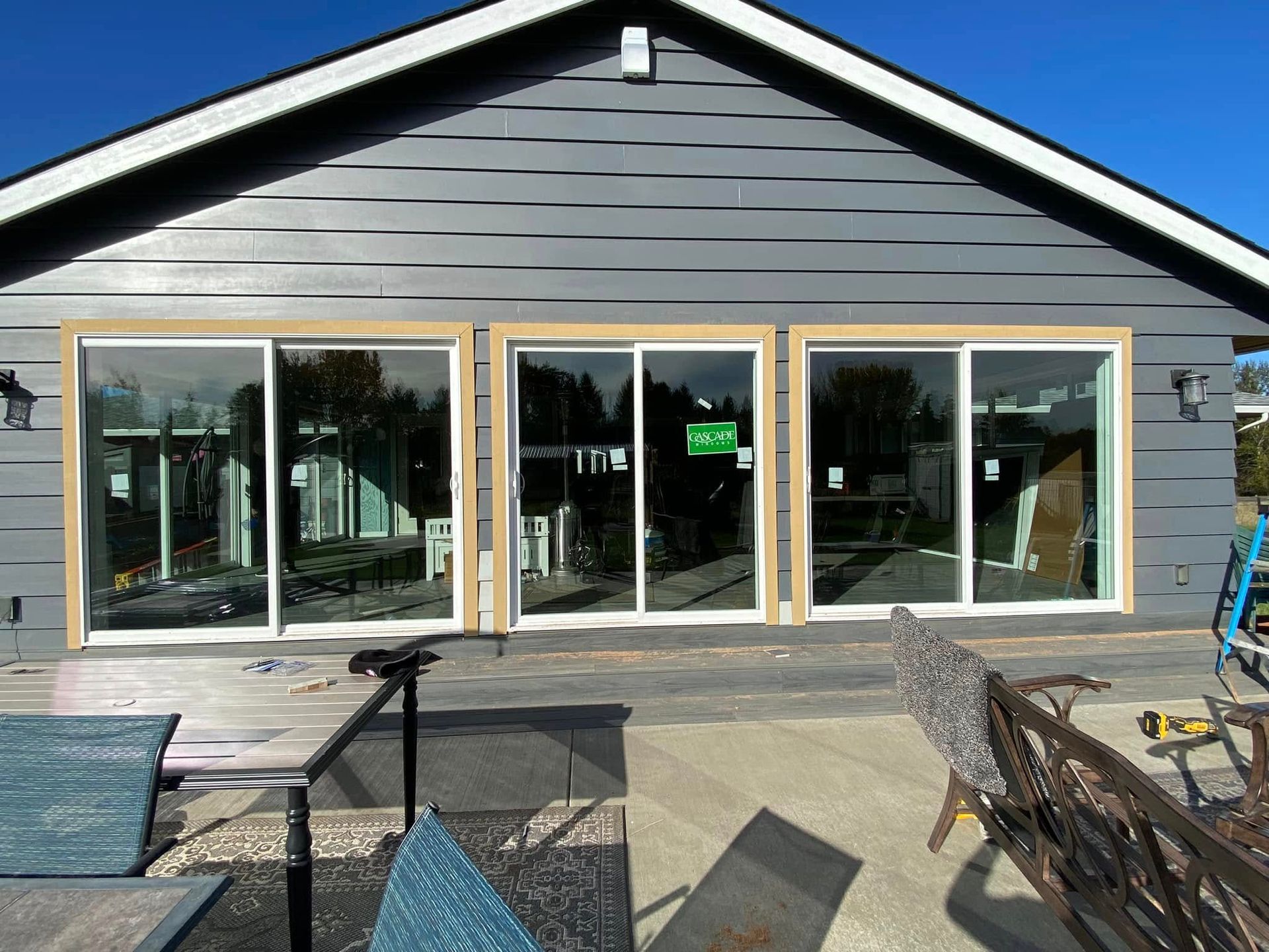 Modern gray house exterior with large glass doors and windows on a patio.