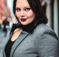 Nicole Glisar wearing a stylish grey jacket and purple lipstick.