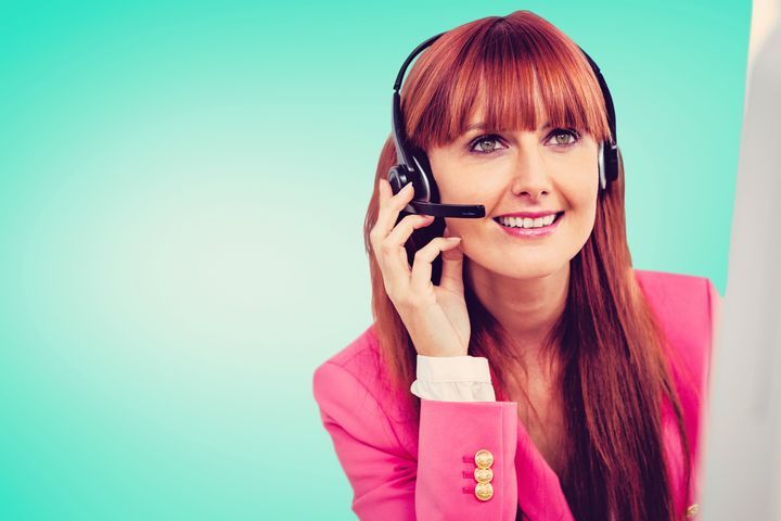 A happy telecommunications representative wearing a headset talking on the phone.