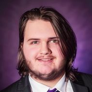 CEO Draven Glisar with shoulder length hair and dressed in a sharp suit and tie exuding confidence and elegance.