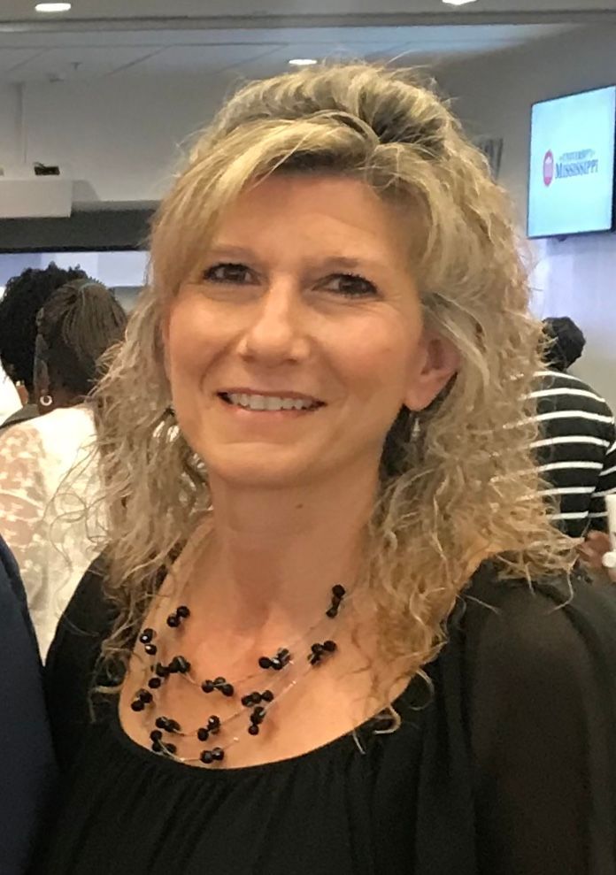 A man in a suit shakes hands with another man in a blue shirt