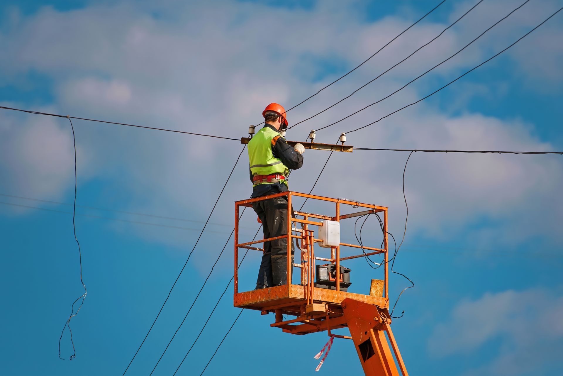 Lineman in Orange Lift Repairing Power Lines Against a Blue Sky — SJD Electrical Contracting in Lithgow, NSW