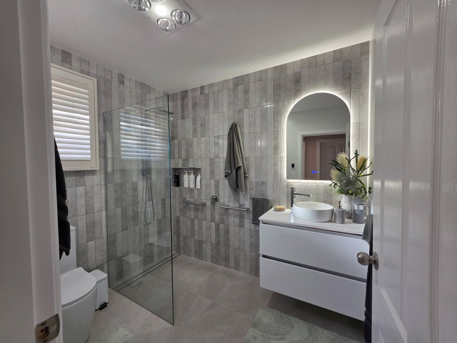 Modern bathroom with gray tiled walls, white vanity, and glass shower— SJD Electrical Contracting in Orange, NSW