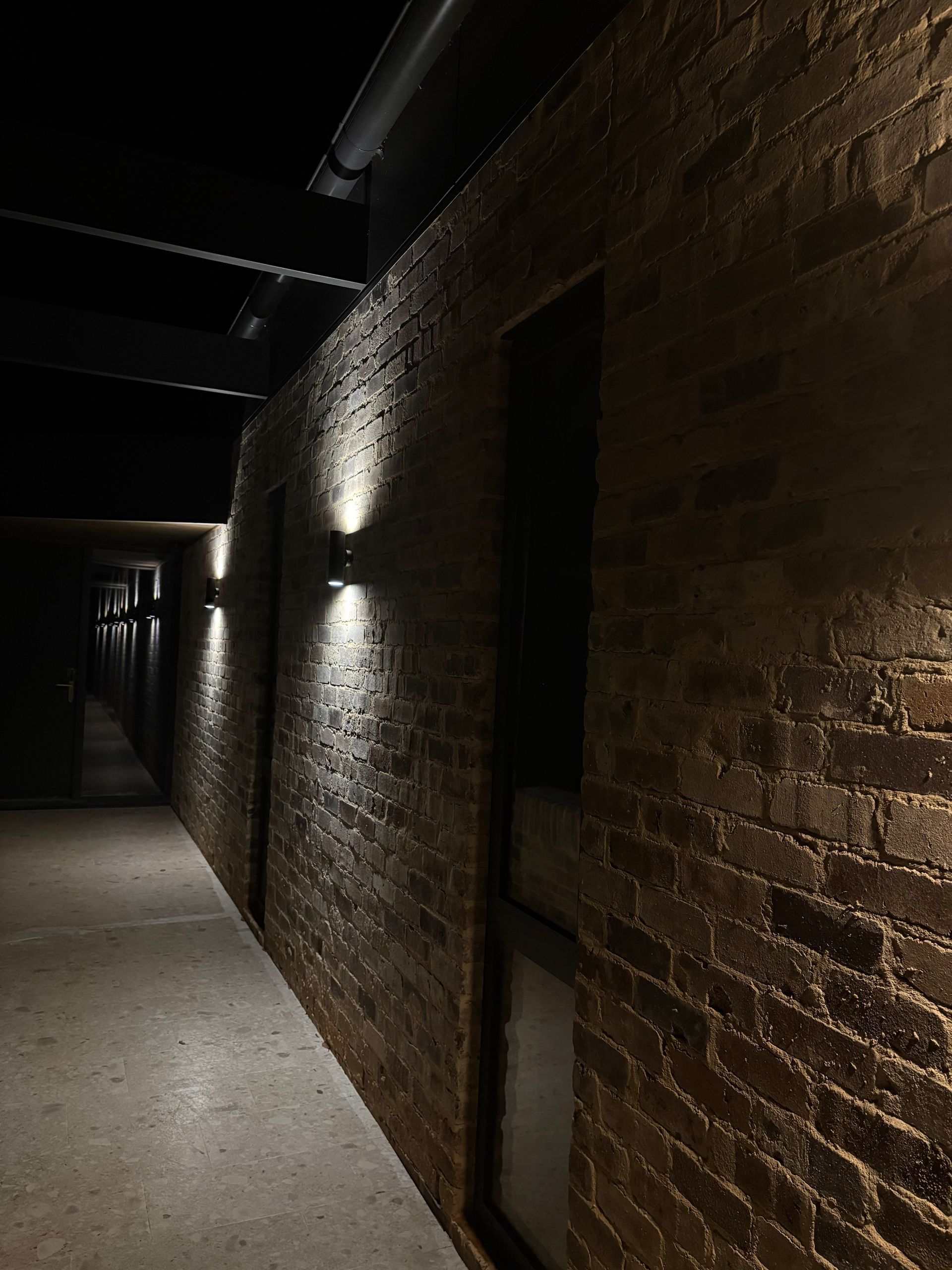Brick wall with recessed lighting in a dark hallway.