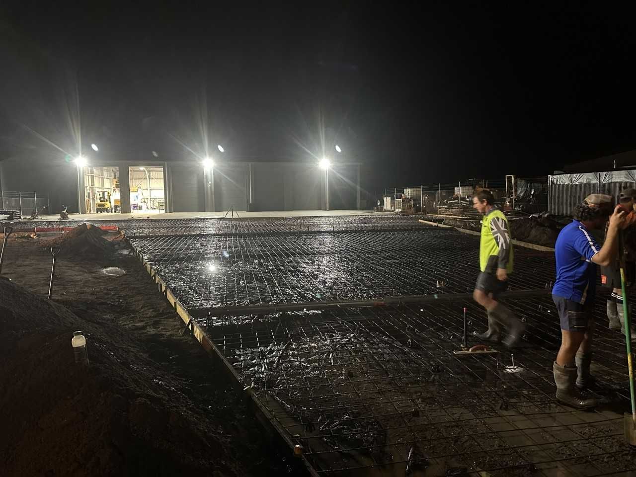 A Group of Construction Workers Are Working on A Construction Site at Night — Wieland Contracting In Tolga, QLD
