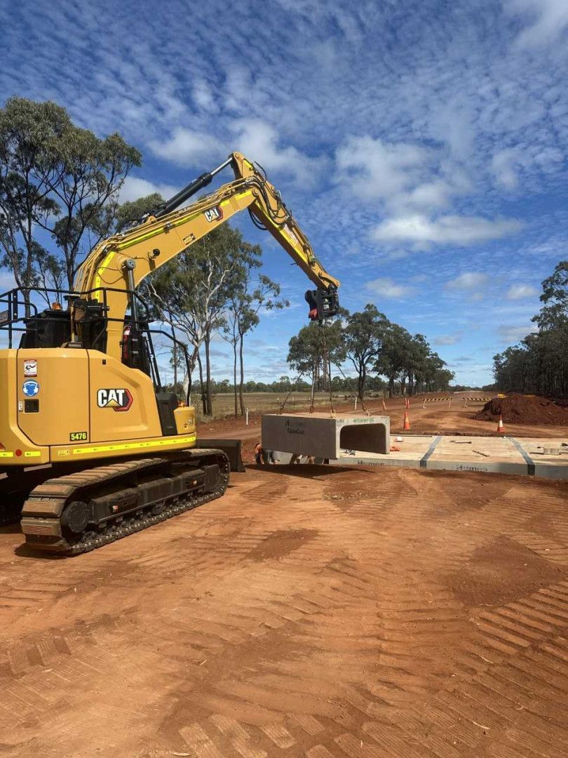 An Excavator is Lifting A Concrete Pipe Section Into Place — Wieland Contracting In Tolga, QLD