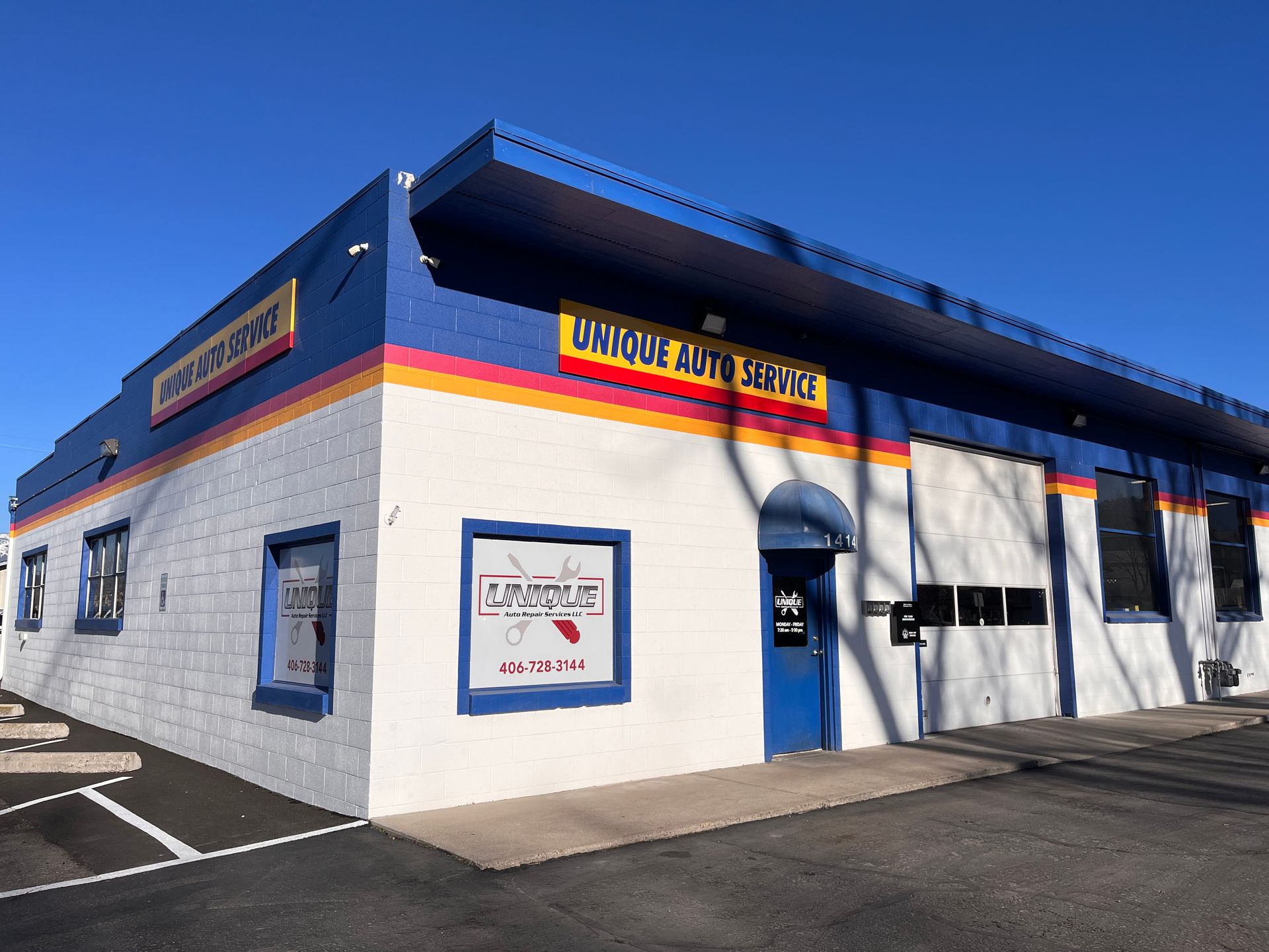 Exterior view of an auto repair shop with white walls, a blue roof, and a blue door.