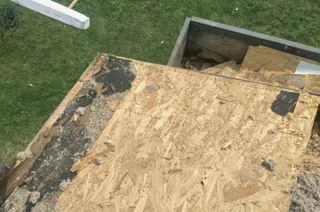 An overhead view of a roof under construction, showing plywood sheathing and patches of old black roofing felt.