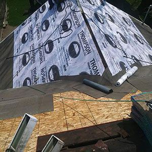 A partially shingled roof under construction with Thompson-branded underlayment applied over plywood decking.