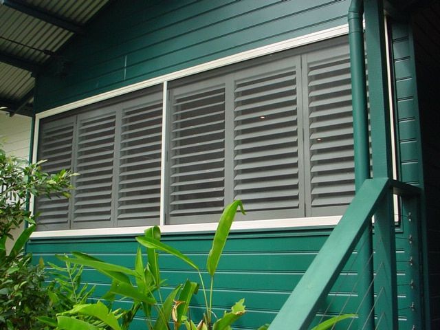 A Green House With A Window With Shutters On It — Balcony Shutters Australia In Moffat Beach, QLD