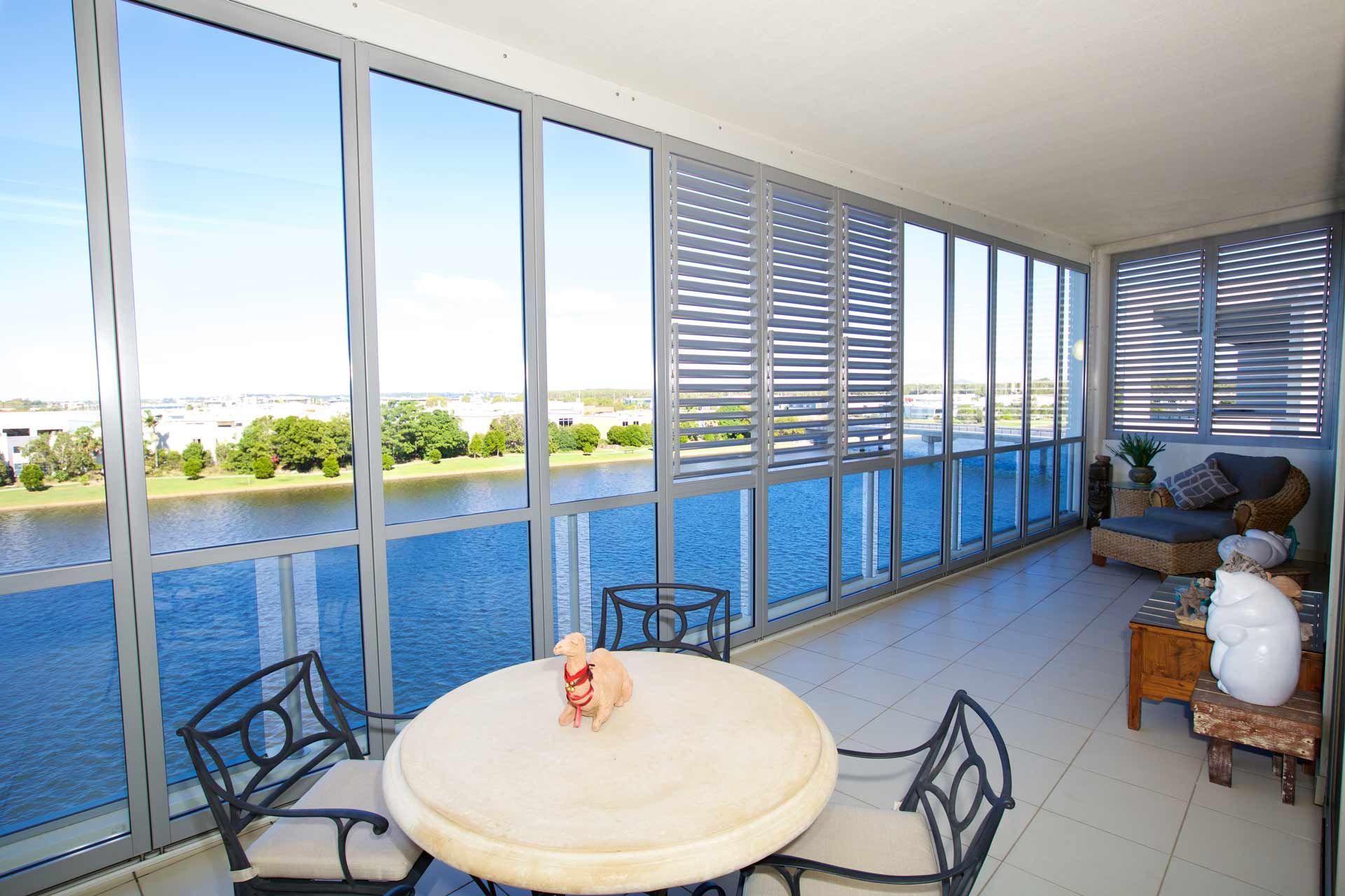A Table And Chairs On A Balcony Overlooking A Body Of Water — Balcony Shutters Australia In Moffat Beach, QLD