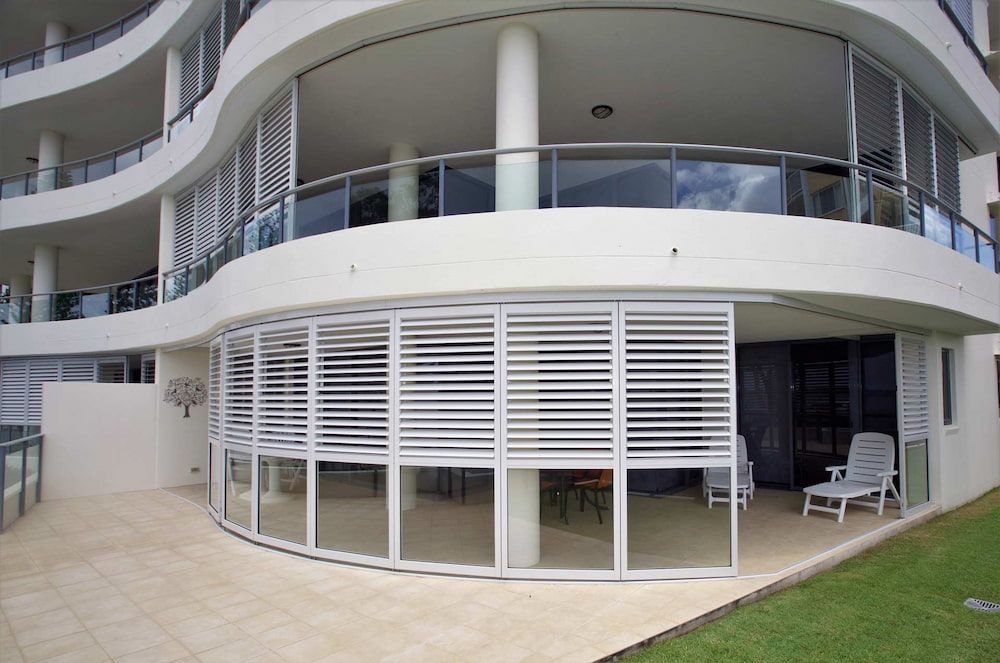 A Large White Building With A Curved Balcony — Balcony Shutters Australia In Moffat Beach, QLD