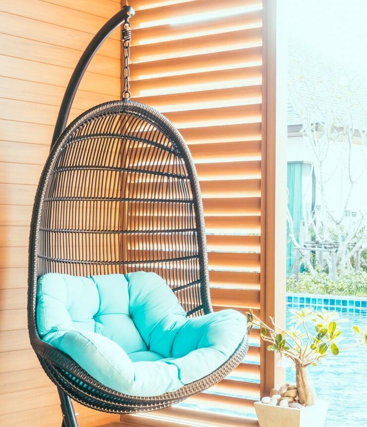 A Hanging Chair Is Sitting In Front Of A Window — Balcony Shutters Australia In Moffat Beach, QLD