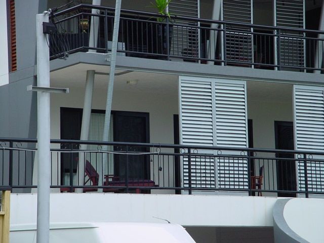 A Balcony With White Shutters And A Black Railing — Balcony Shutters Australia In Moffat Beach, QLD