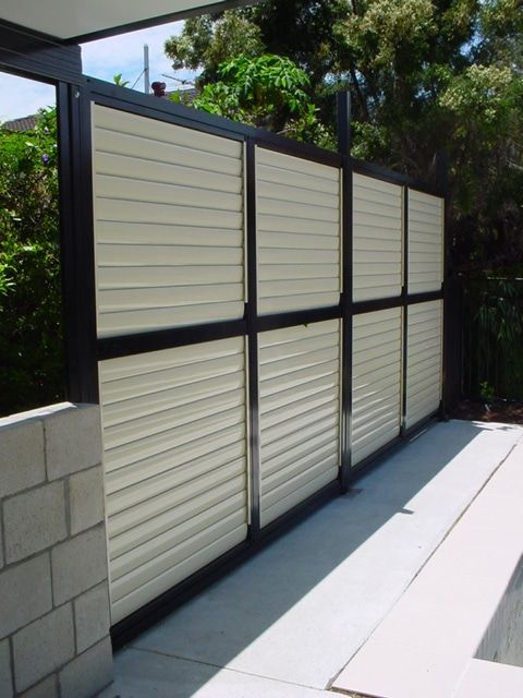 A White And Black Fence With A Brick Wall In The Background — Balcony Shutters Australia In Moffat Beach, QLD
