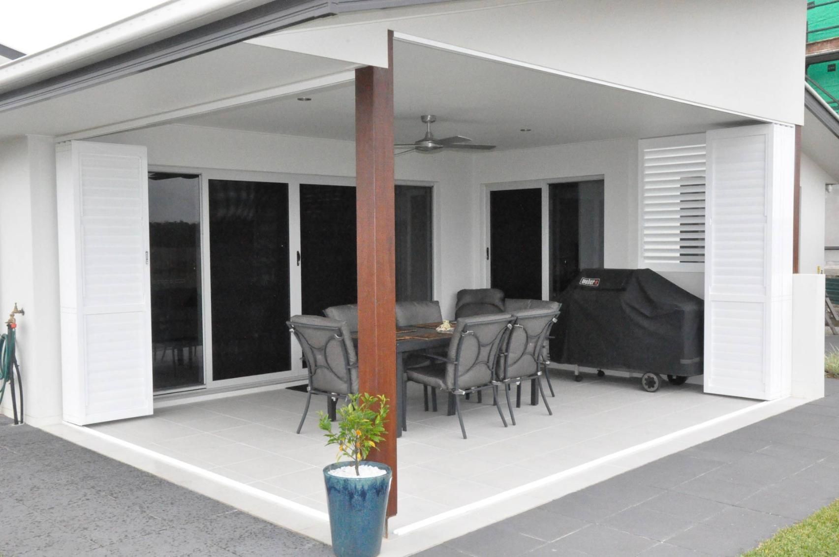 A Patio With A Table And Chairs And A Potted Plant — Balcony Shutters Australia In Moffat Beach, QLD