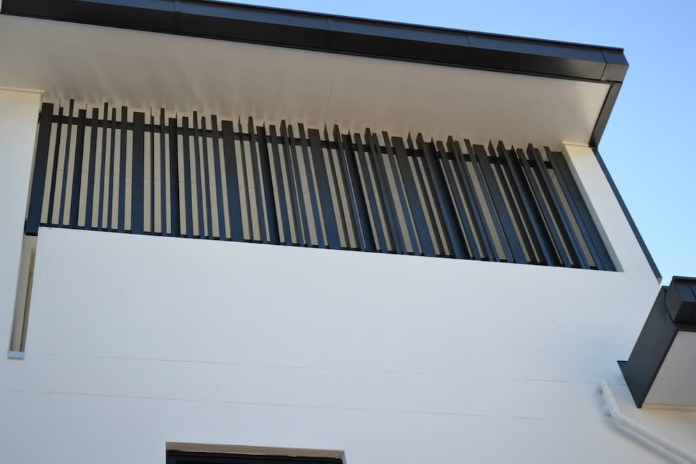 Modern Building Facade Featuring a White Wall and a Sleek Black Metal Grille Balcony