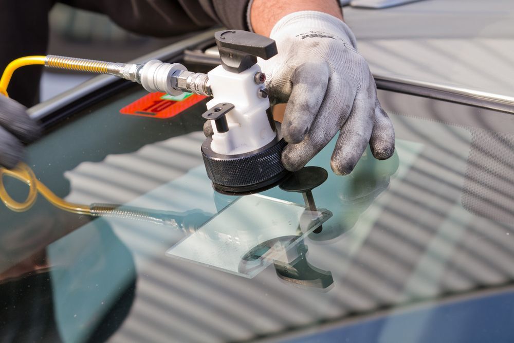 A person is repairing a windshield with a tool.
