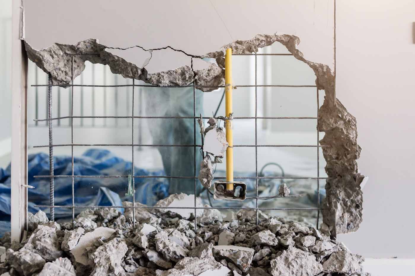 A hole in a wall is being filled with rocks and concrete.