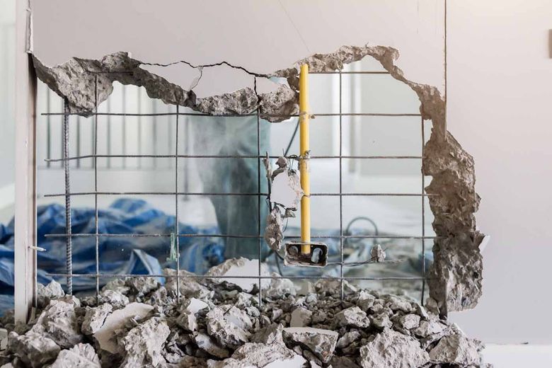A hole in a wall is being filled with rocks and concrete.